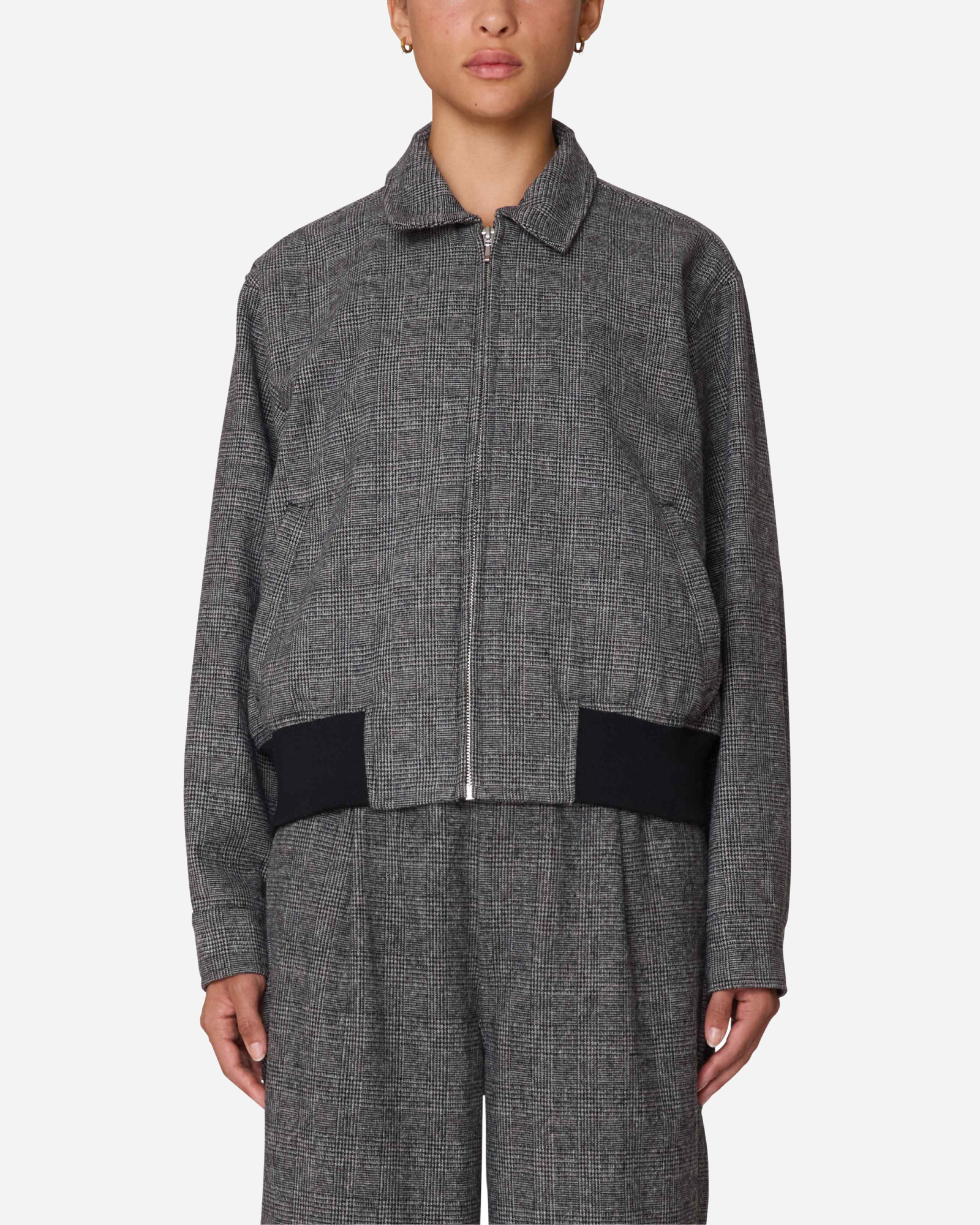Person wearing a gray textured jacket with black accents on a white background
