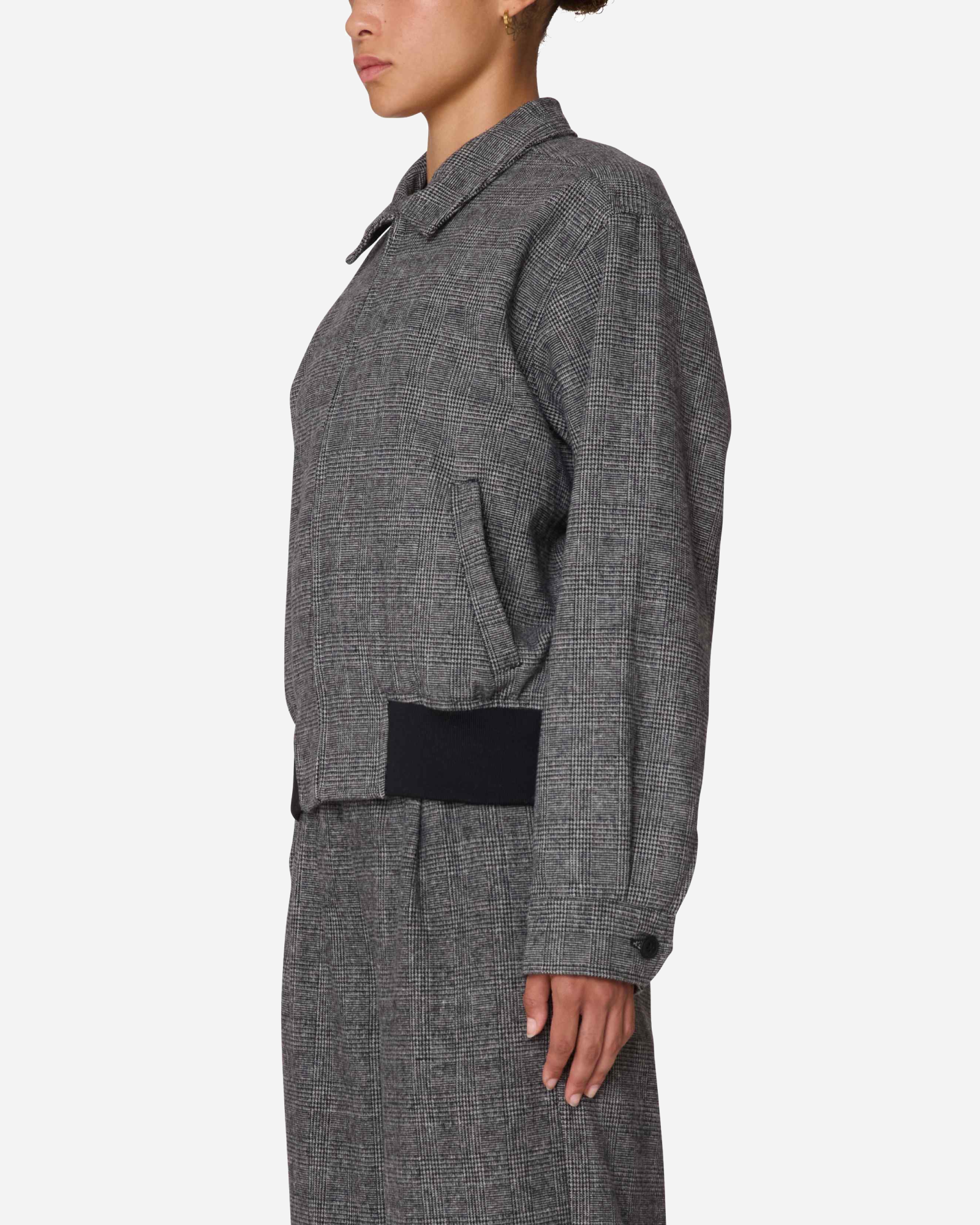 Person wearing a gray checkered jacket with a black patch on a white background